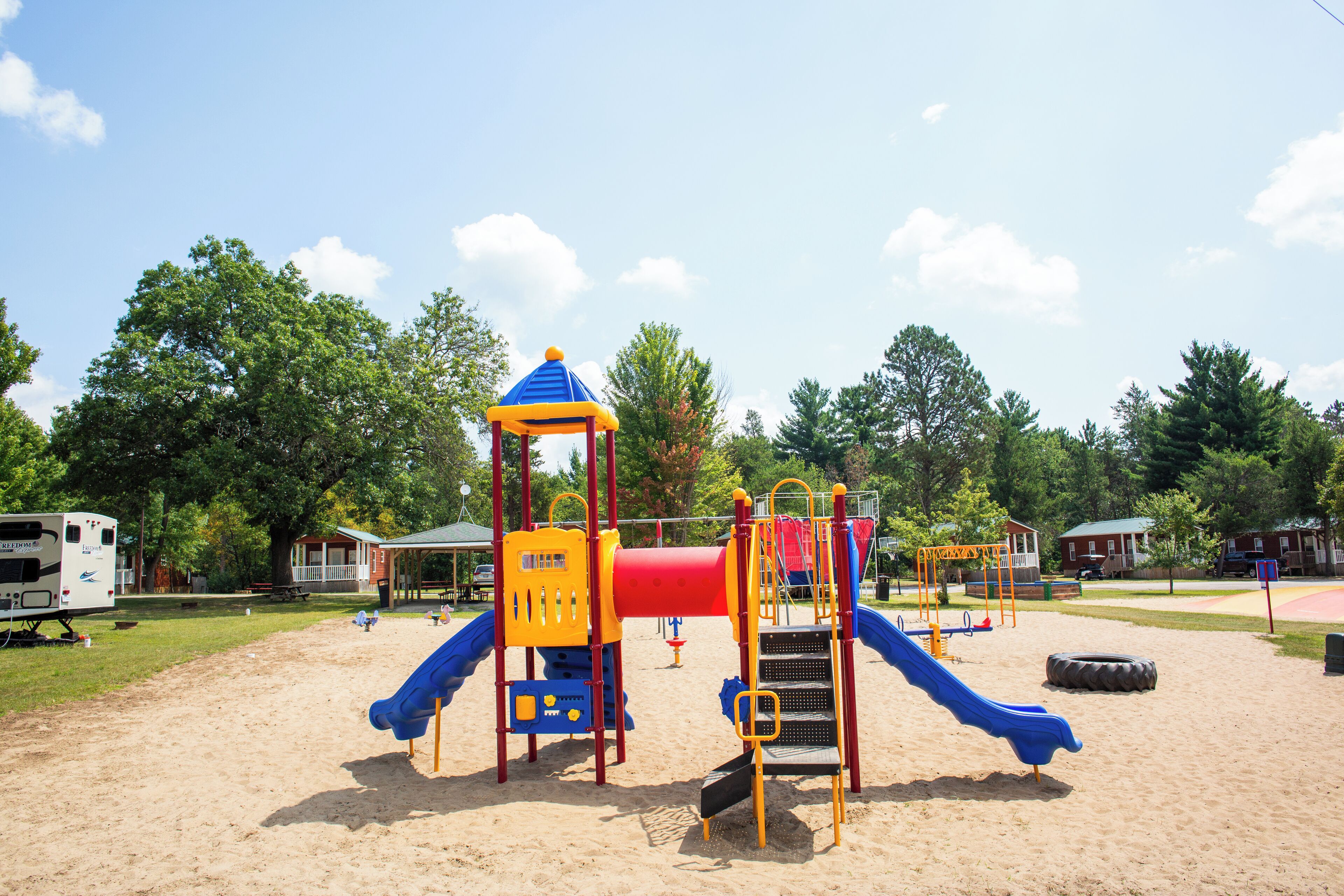 A playground with a slide, climbing structures, and a covered area.