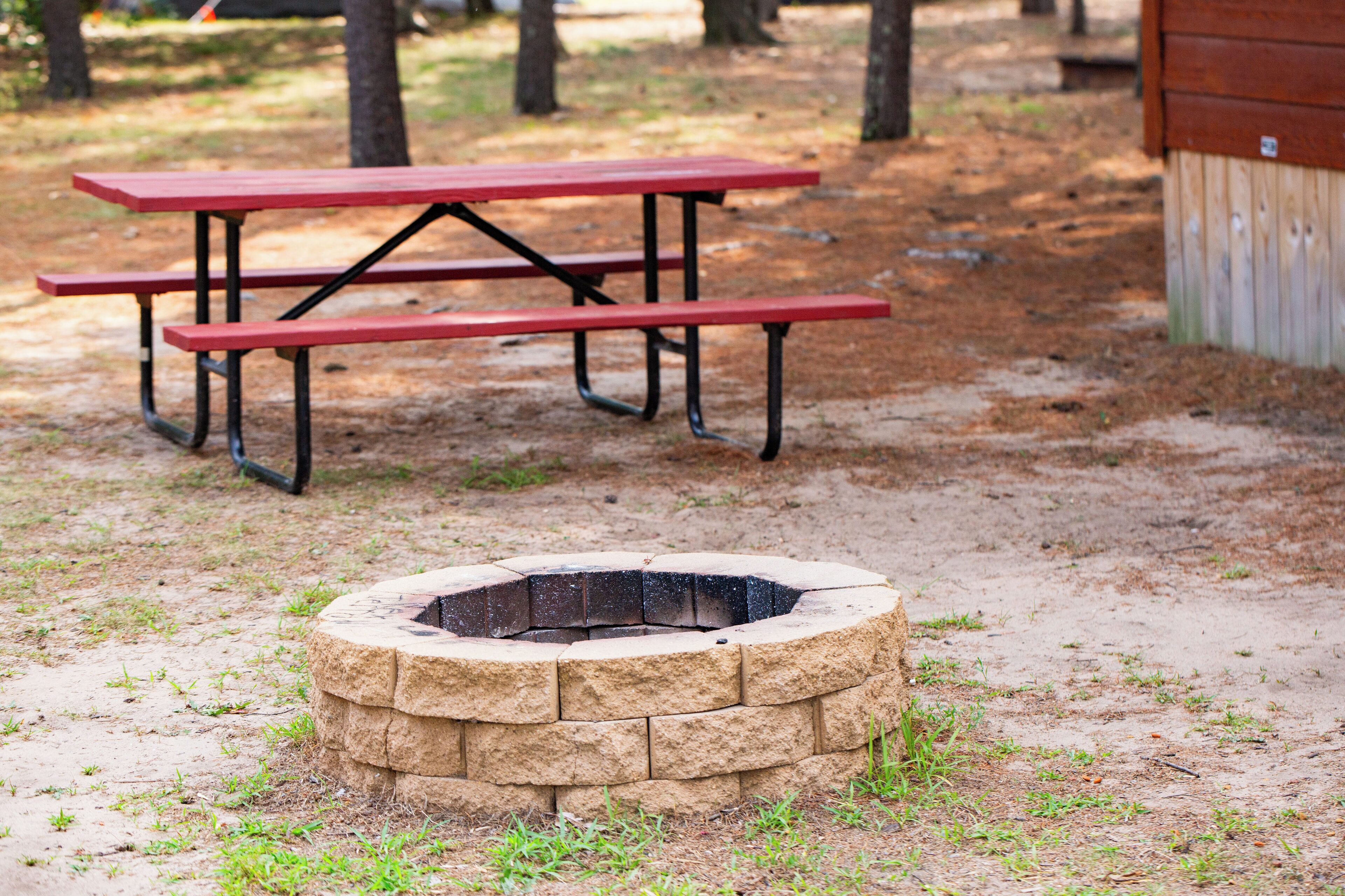 A picnic table and a stone fire pit in a park.