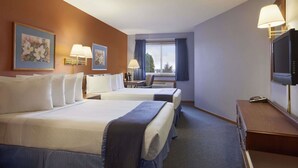 A hotel room with two beds, a desk, a TV, and a window with curtains. - Travelodge by Wyndham Motel of St Cloud (St Cloud)