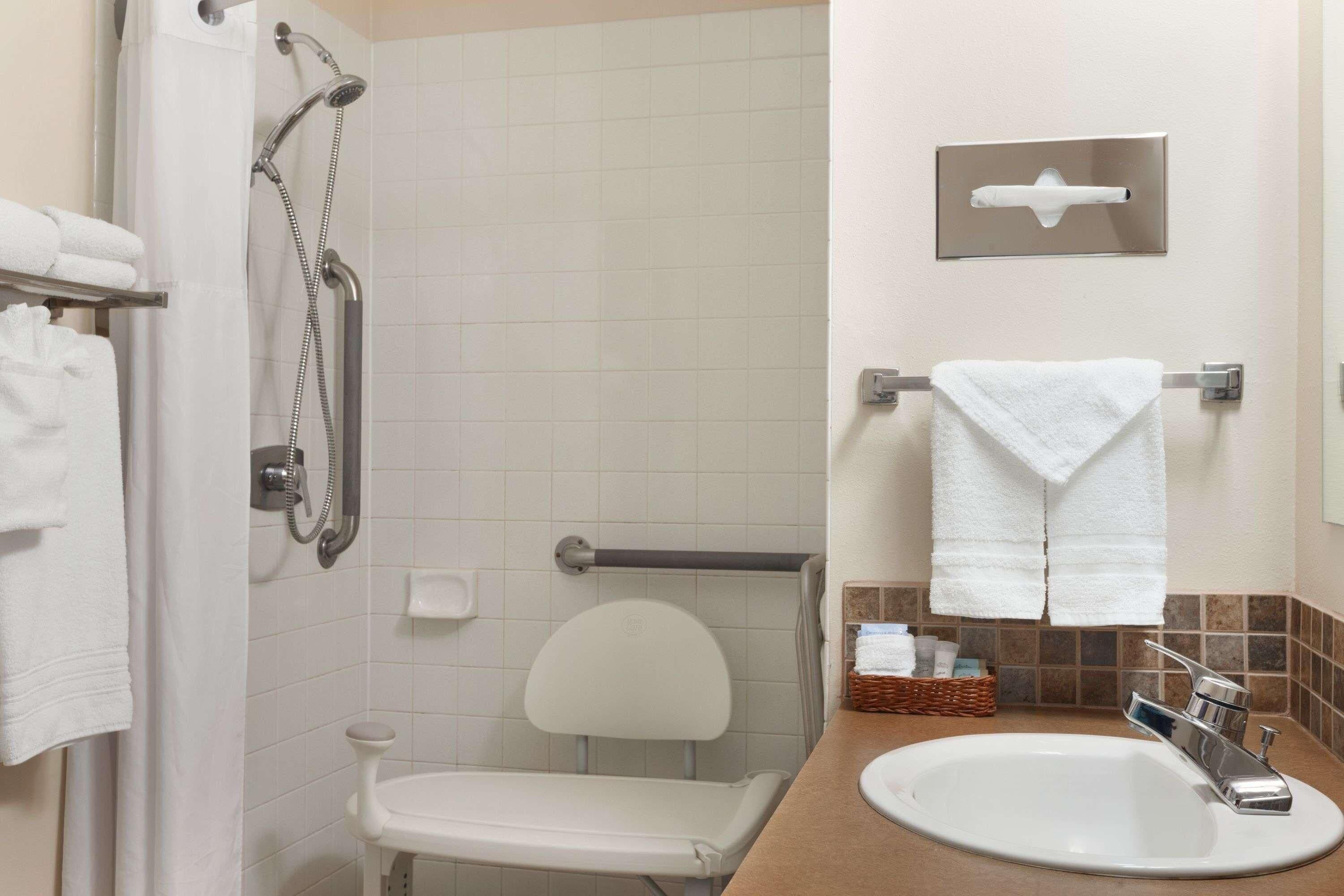 Baño con ducha, inodoro, lavamanos y toallero.