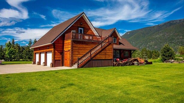 A wooden cabin with a balcony, a staircase, and a driveway. - Mountain View Studio Apartment, Close to GNP (Columbia Falls)