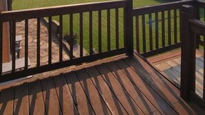 A wooden deck with a view of a green landscape and mountains in the distance. - Mountain View Studio Apartment, Close to GNP (Columbia Falls)