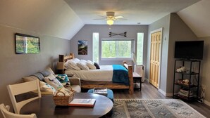 A cozy loft bedroom with a bed, a desk, and a TV. - Mountain View Studio Apartment, Close to GNP (Columbia Falls)