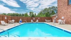A rectangular swimming pool with a 3½ ft depth, surrounded by white lounge chairs and a brick building. - Super 8 by Wyndham Georgetown (Georgetown)