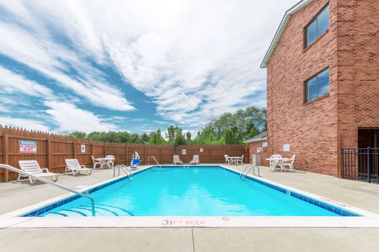 A swimming pool with lounge chairs and a wooden fence.