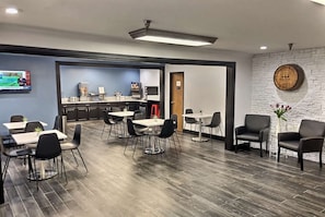 A modern hotel lobby with a kitchen area, dining tables, and chairs. - Super 8 by Wyndham Georgetown (Georgetown)