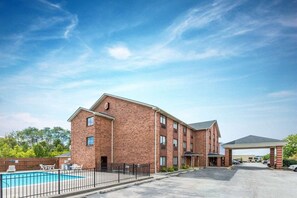 A multi-story brick building with a swimming pool and a covered parking area. - Super 8 by Wyndham Georgetown (Georgetown)