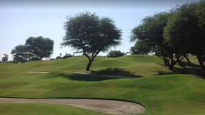 A golf course with rolling green hills, trees, and a sand bunker. - Remodeled condo on PGA West's Stadium Golf Course (La Quinta)