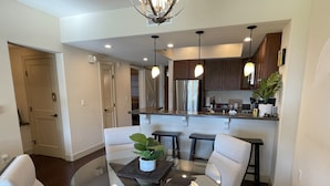 A modern kitchen with dark wooden cabinets, a central island with a glass top, and pendant lighting. - Secluded 2-Suite - Stocked Like you're at home. Ocean front pool, private lanai (Waikoloa Village)