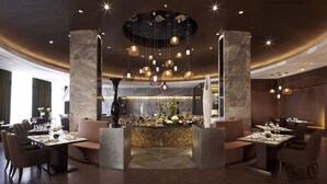 A modern restaurant with a central island, multiple seating areas, and a decorative ceiling with hanging lights. - Mission Hills Resort Haikou (Haikou)