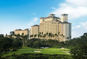 A large hotel with multiple floors, surrounded by lush greenery and a golf course.