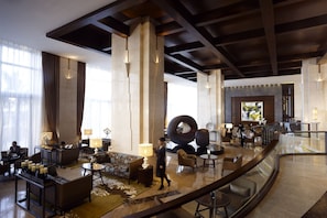 A spacious lobby with high ceilings, large windows, and a central seating area with sofas and tables.