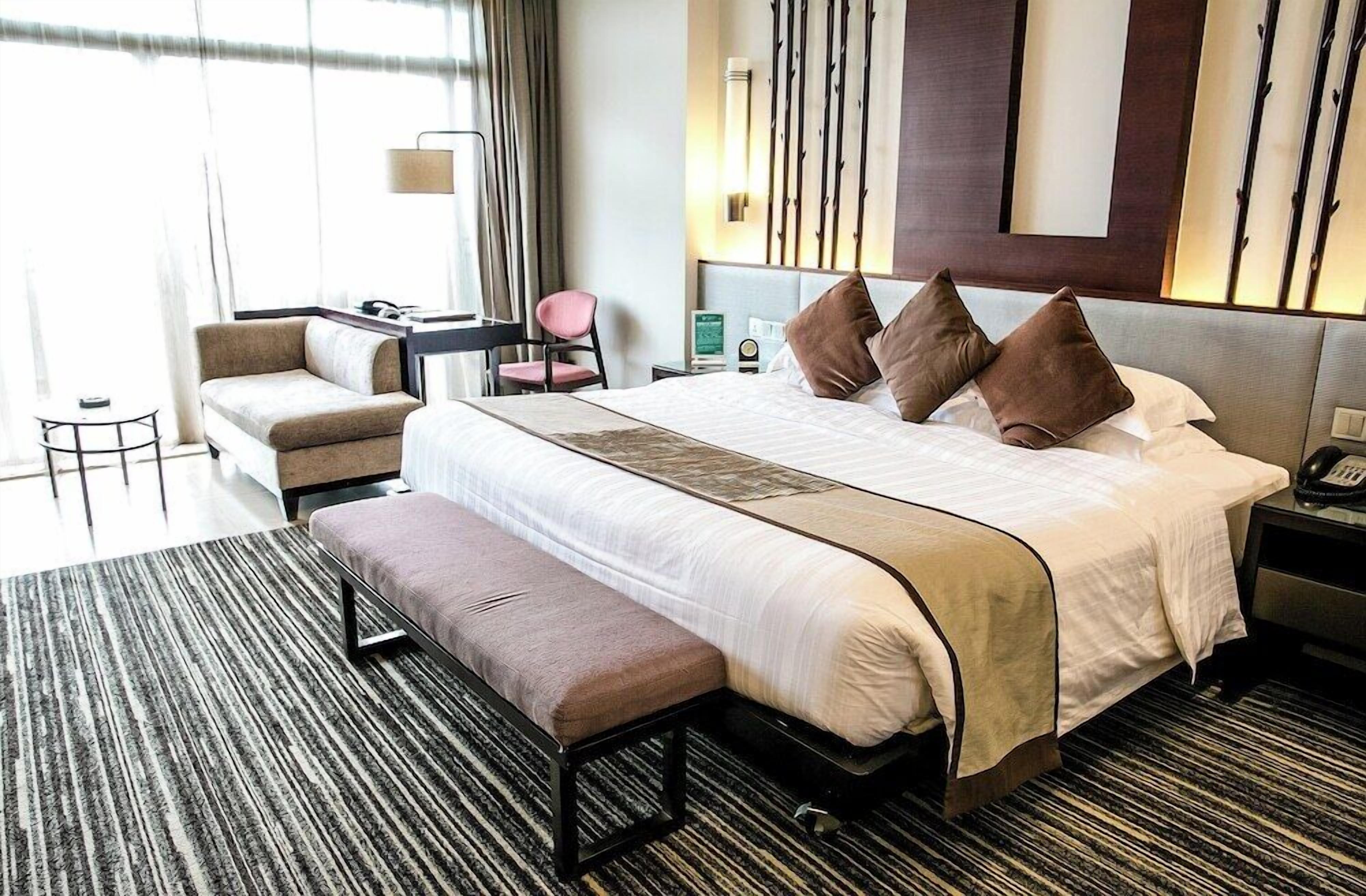Une chambre d’hôtel avec un grand lit, une banquette, un bureau et une chaise.