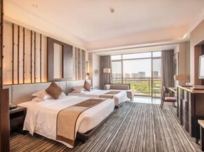 Une chambre d’hôtel avec deux lits, un bureau et une grande fenêtre donnant sur la ville.