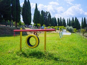 A playground with a tire swing and a red and yellow play structure. - Pian Dei Mucini Resort (Massa Marittima)