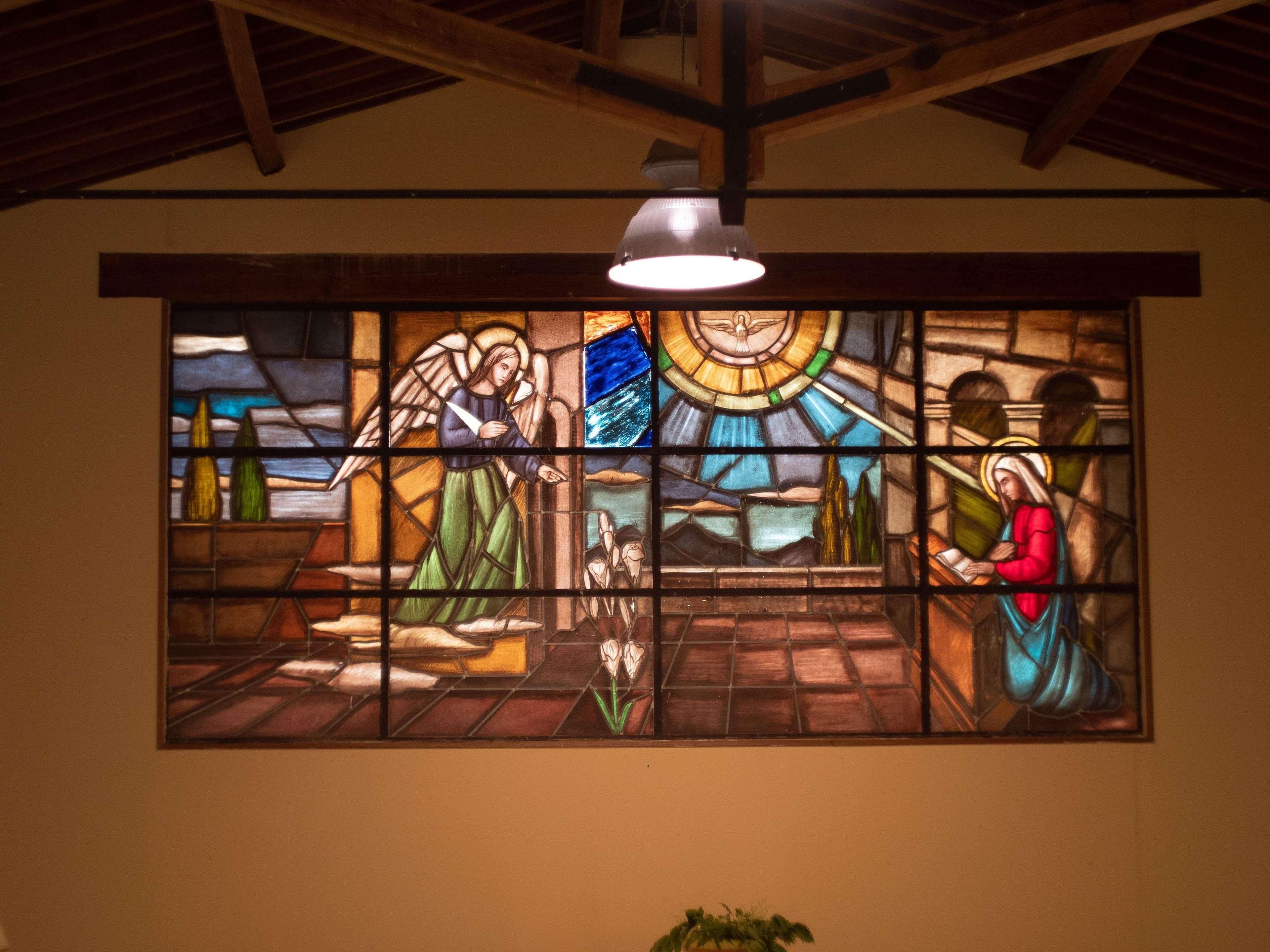 A stained glass window depicting a religious scene with figures and a dove.