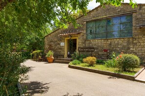 A stone building with a reception sign, surrounded by greenery and potted plants. - Pian Dei Mucini Resort (Massa Marittima)