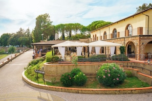 A restaurant with outdoor seating, a stone wall, and a sign indicating its location. - Pian Dei Mucini Resort (Massa Marittima)