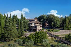 A historic building with multiple levels, surrounded by lush greenery and a stone bridge. - Pian Dei Mucini Resort (Massa Marittima)