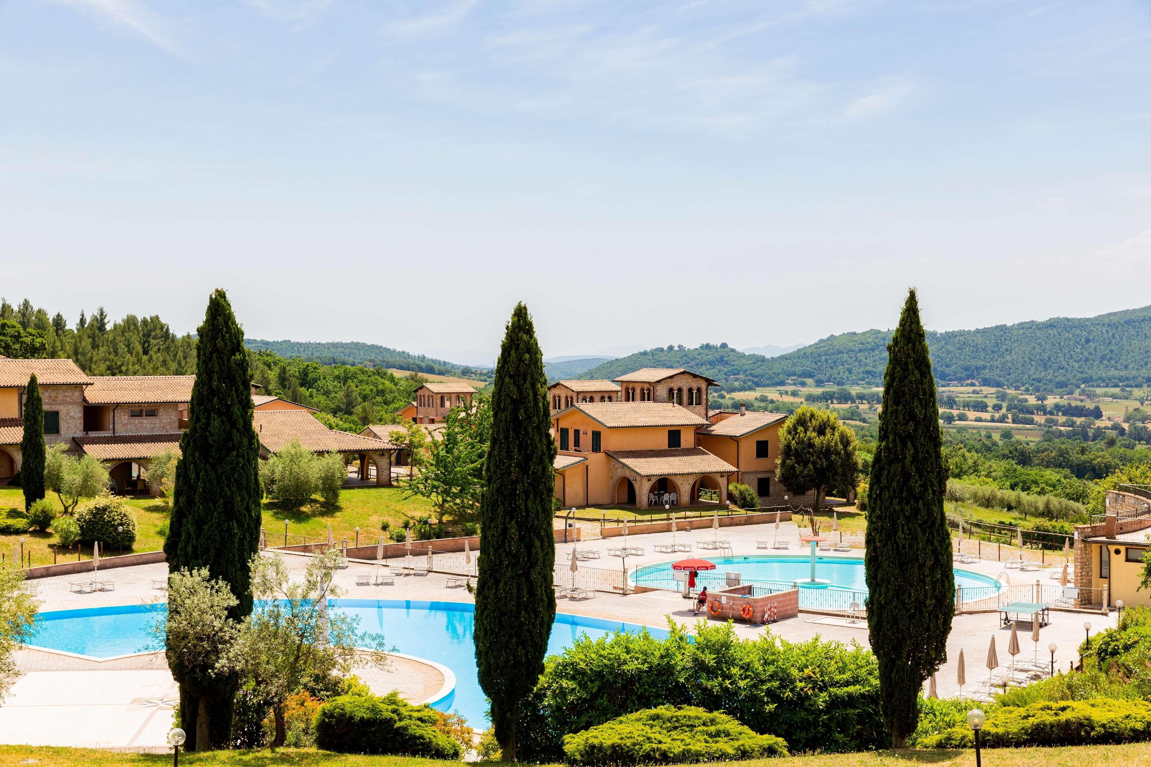 Ein Resort mit Schwimmbad, mehreren Gebäuden und umgebender Bepflanzung.