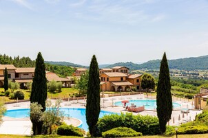Un complejo turístico con piscina, varias edificaciones y follaje circundante.