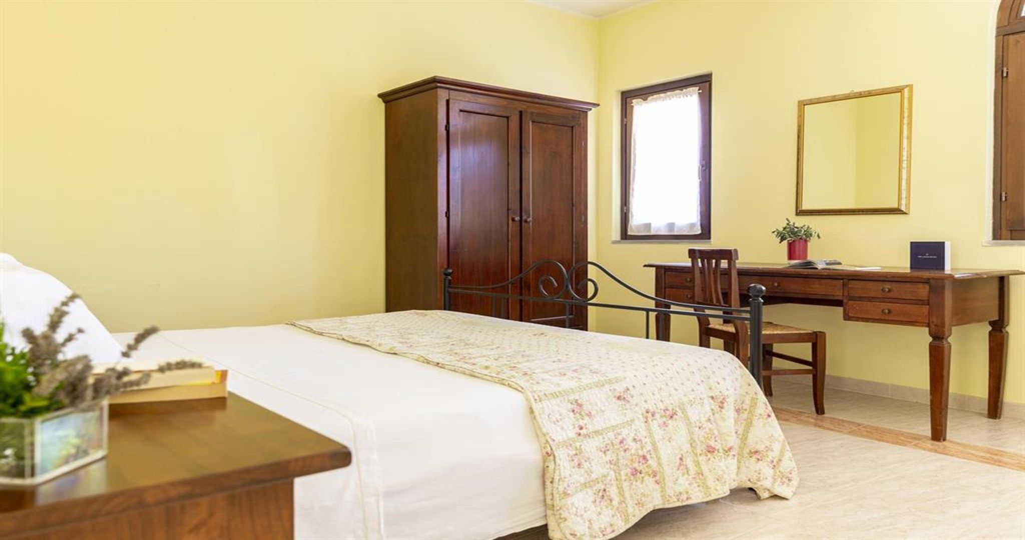 Una camera da letto con un letto, un armadio in legno, una scrivania e uno specchio.