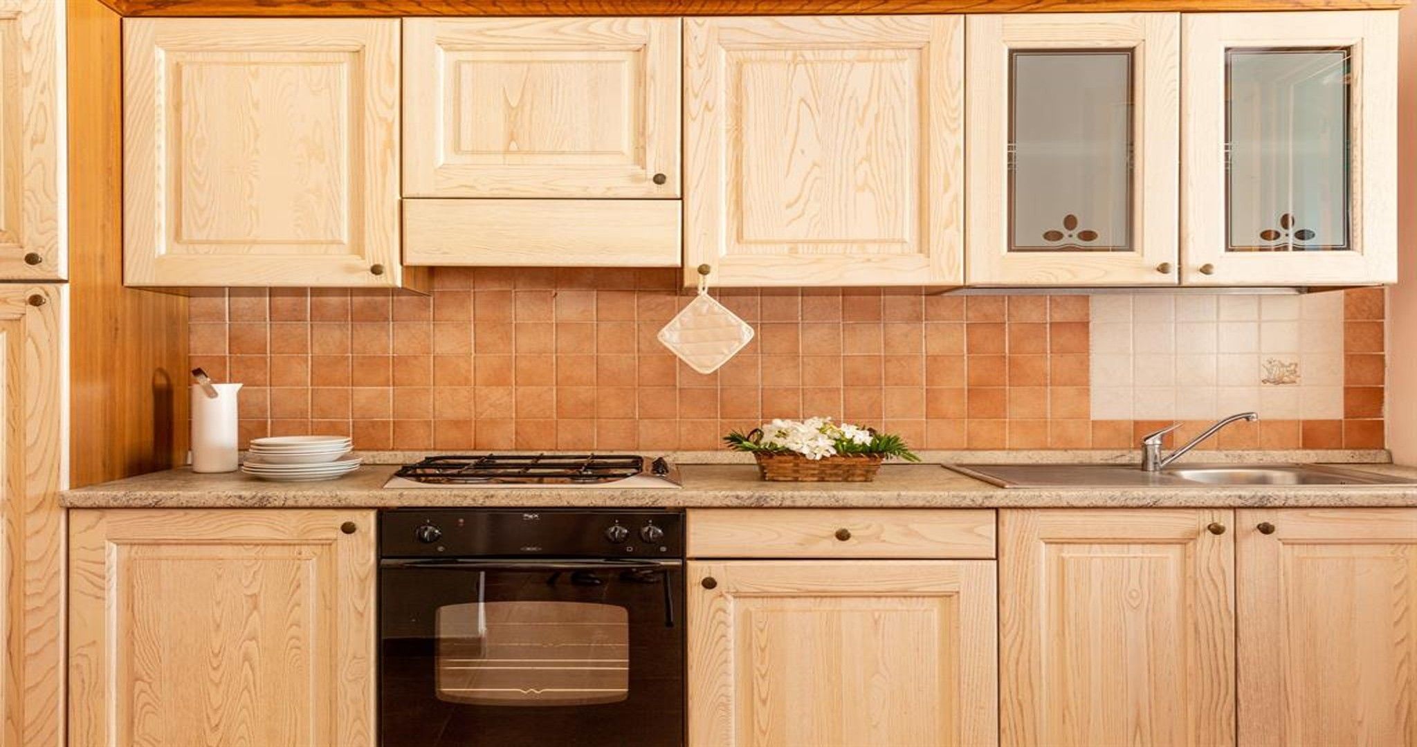 Una cucina con mobili in legno, un piano cottura, una lavastoviglie e un lavandino.