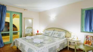 Una camera da letto con un letto, un comodino, una sedia, uno specchio e una porta.