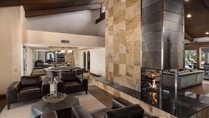 A spacious living area with a fireplace, leather sofas, and a stone accent wall.