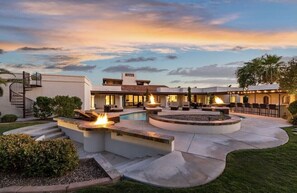A modern outdoor pool area with fire pits, a staircase, and a covered seating area.