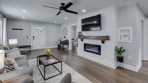 Un salon moderne doté d’une cheminée, d’un ventilateur de plafond et d’un téléviseur à écran plat fixé au-dessus de la cheminée.