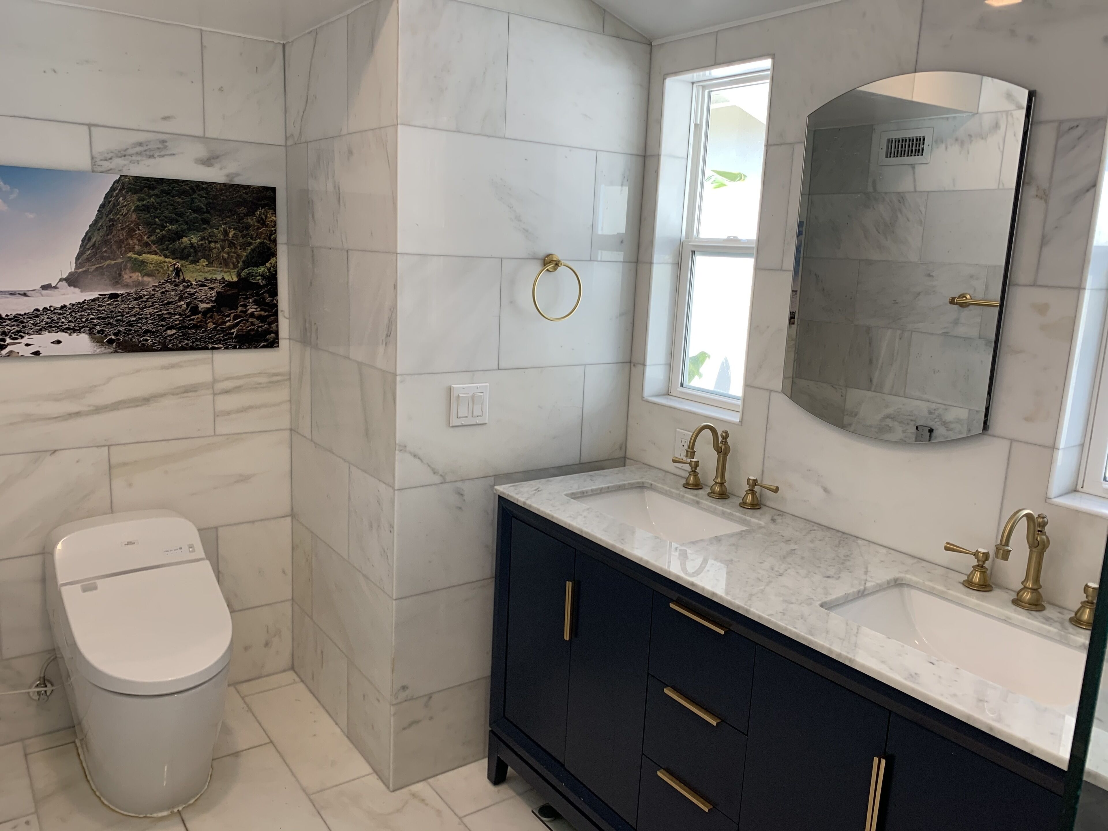Ein Badezimmer mit einer weißen Toilette, einem Waschbecken mit goldenen Armaturen und einem großen Spiegel.