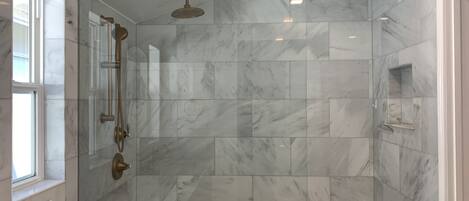 A modern bathroom with a shower, a vanity with a sink, and marble tiles.