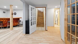 A modern interior with a wooden staircase, a bar area with stools, and a large glass door. - Cozy, quiet and private retreat at Cottage Spa & Lake Villa Sinaia, amazing view (Chertsey)
