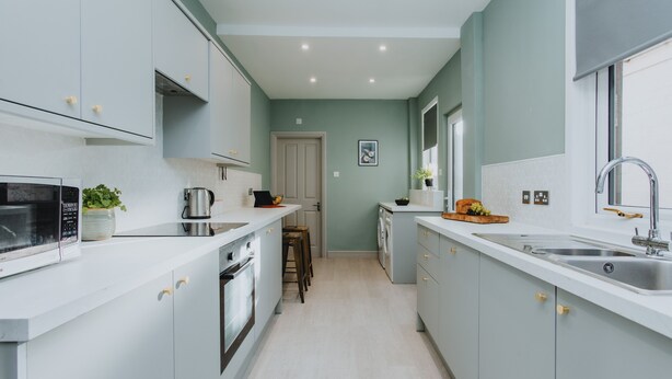 Een moderne keuken met witte kasten, een magnetron, een koffiezetapparaat en een spoelbak.