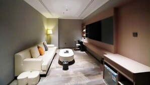 A modern hotel room with a sofa, a coffee table, a TV, and a desk. - Dongsheng · Yuyuan Hotel (Qixia)