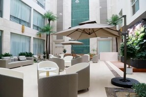 A spacious indoor area with seating arrangements, a large umbrella, and indoor plants.