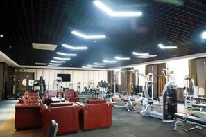 A gym with exercise equipment, red seating, and a modern ceiling design.
