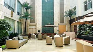 A spacious lobby with a central column, seating area, and potted plants. - Dongsheng · Yuyuan Hotel (Qixia)