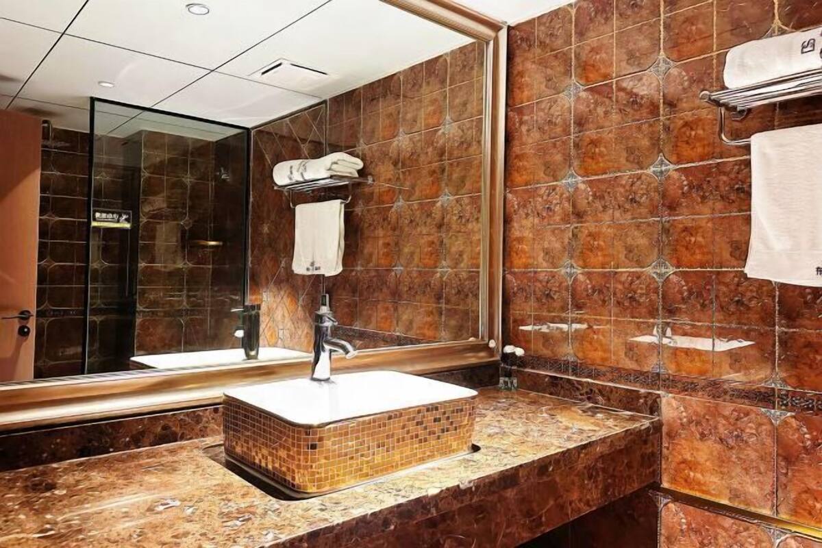 A bathroom with a marble sink, a glass shower enclosure, and a large mirror.
