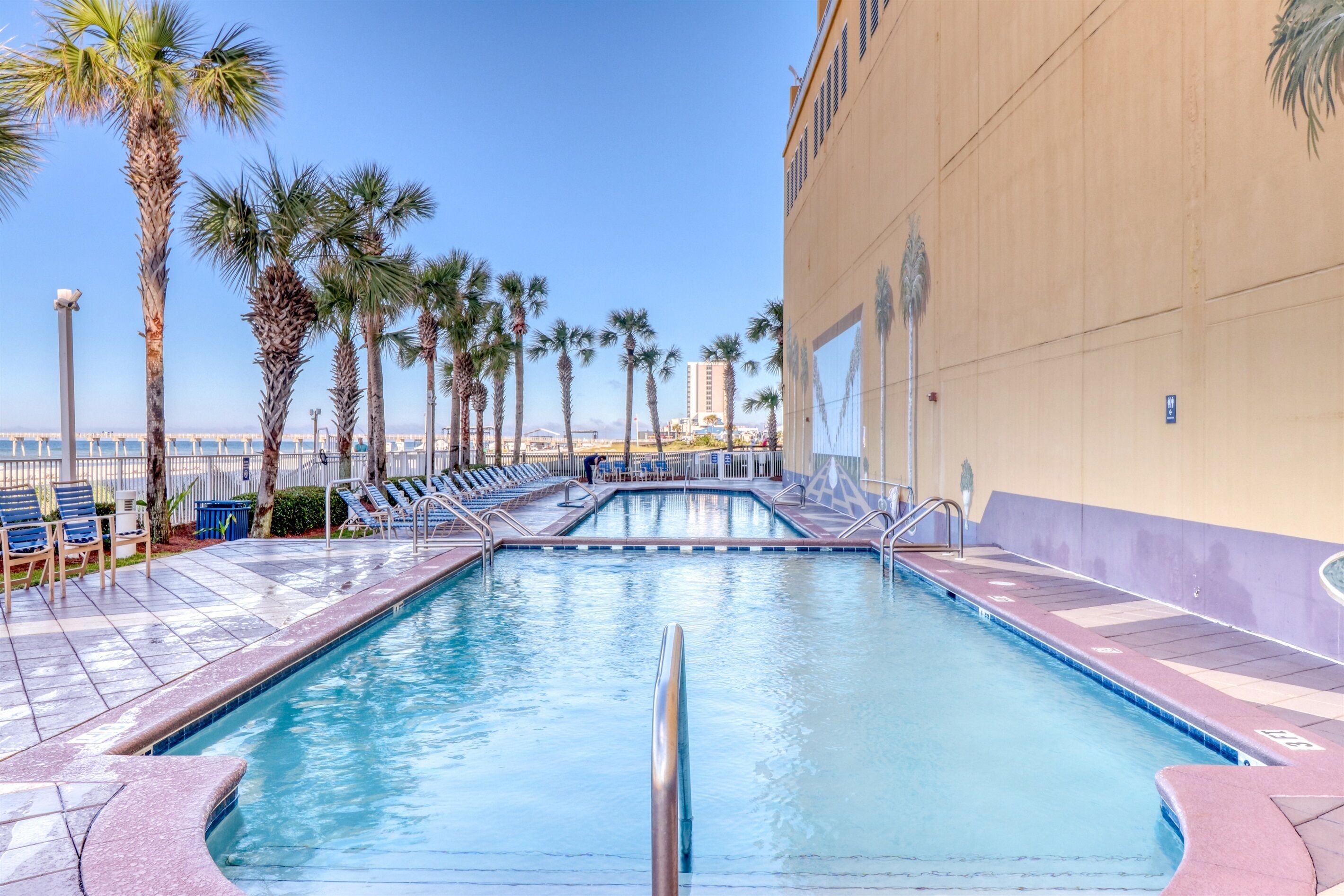 A swimming pool with lounge chairs and palm trees.