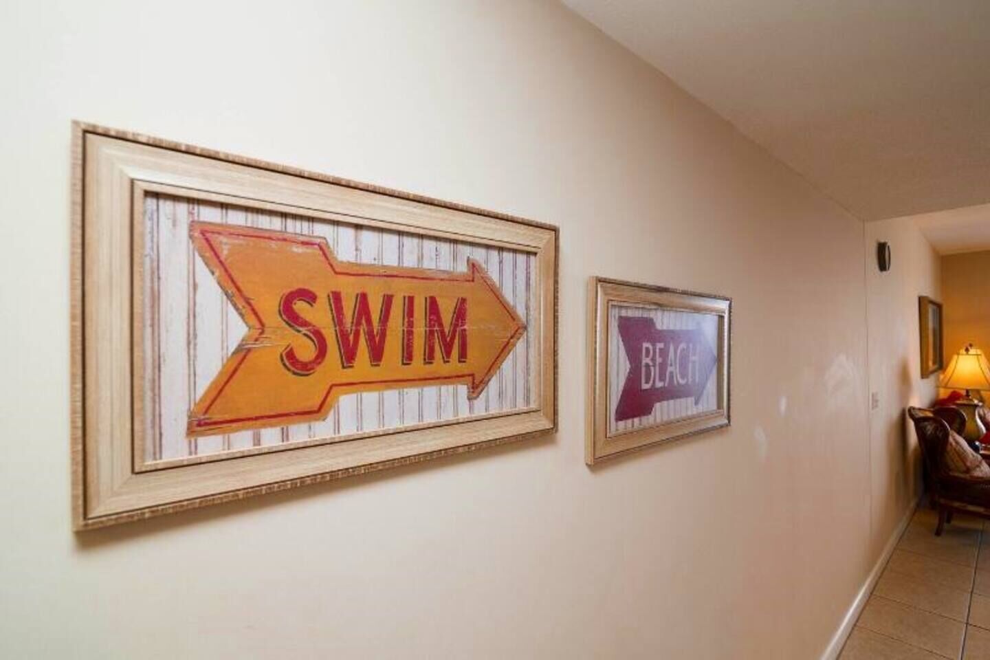 Zwei gerahmte Schilder an einer Wand, eines mit der Aufschrift 'SWIM' und das andere mit 'BEACH'.