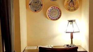 Een kamer met een bureau, een lamp en drie decoratieve borden aan de muur.