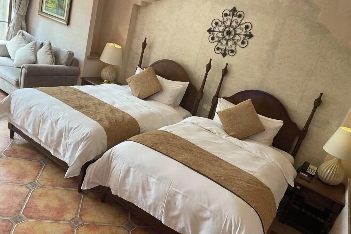 Une chambre d’hôtel avec deux lits, un canapé et un élément décoratif mural.