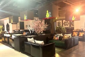 A reception area with black seating, a decorative tree, and wall-mounted artwork. - Shanghai Xuhui Yuanshitian Hotel (Shanghai)