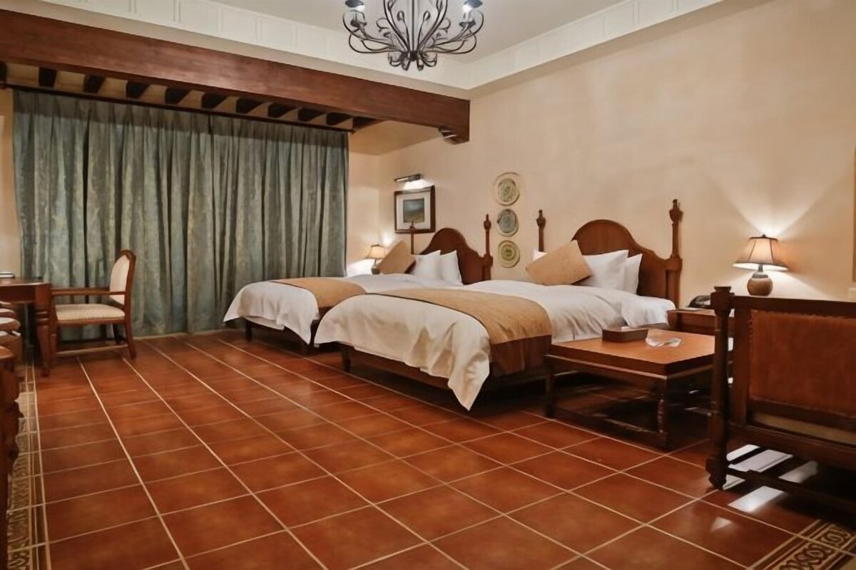 Una habitación de hotel con dos camas, un cabecero de madera, un escritorio y una silla.