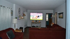 A living room with a television, red sofas, a small table, and a lamp.