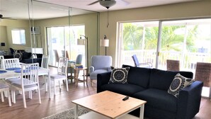 A living room with a dark blue sofa, white chairs, a wooden coffee table, and a patterned rug. - STUNNING WATERFRONT 2 BEDROOM BEAUTY.  CLOSE TO EVERYTHING. (Fort Lauderdale)