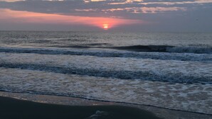 A beach with waves and a sunset.