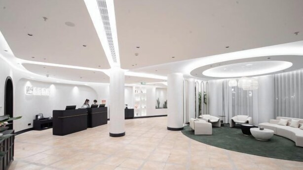 Una hall d'albergo moderna con reception, area salotto e un ampio spazio aperto con colonne.